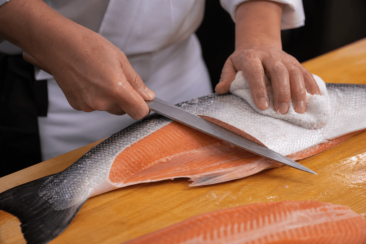 Geste de coupe avec yanagiba : angle de lame et stabilisation du poisson.